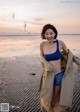 A woman in a blue bikini standing on a beach.