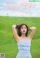 A woman in a blue dress standing in a green field.